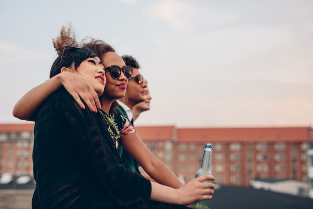 Junge Freunde genießen gemeinsam den Sonnenuntergang auf einem Rooftop.