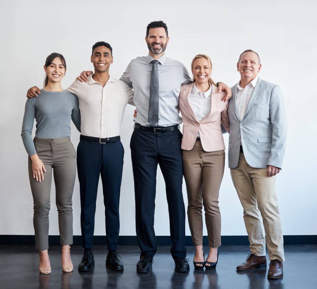 Professionelles, diverses Team posiert lächelnd für ein Gruppenfoto im Büro.